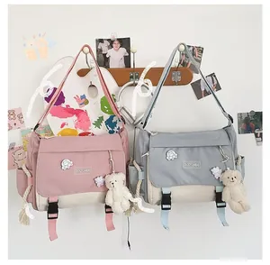 Detail of pink and blue canvas messenger bag with flap buckles and cute bear pendant