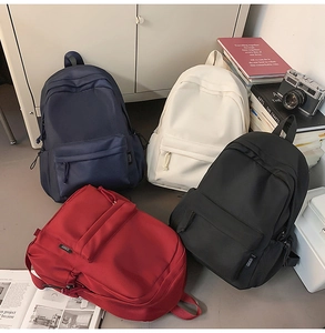 Minimalist waterproof nylon backpacks in four colors shown in a campus study setting