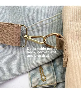 Detail of detachable gold metal hook and woven shoulder strap on corduroy tote bag