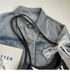 Detail of a black and white striped tote bag with a white lace bow and leather strap