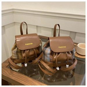 Detail of vintage plaid tweed bucket backpack with leather straps and drawstring closure