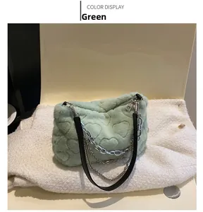 Détail du sac à main en fausse fourrure verte avec motifs cœurs et chaînes argentées
