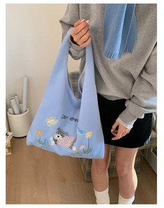 Detailed embroidery of a white puppy and flowers on a light blue knit tote bag