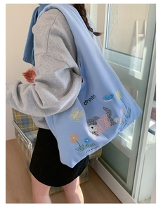 Close-up of light blue canvas tote bag featuring embroidered puppy and flower patterns
