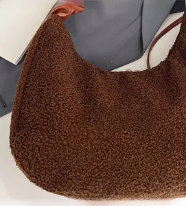 Detail of brown teddy plush crescent bag showing soft lamb wool fabric and leather strap
