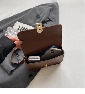 Detail view showing open interior of the dark brown leather crossbody bag and gold latch