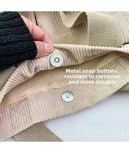 Close-up of the metal magnetic buckle on the corduroy shoulder bag showing the lining