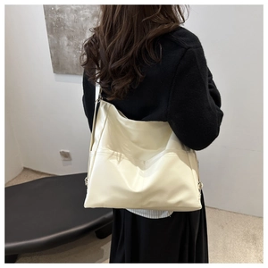 Close-up of a large beige PU leather tote bag worn by a model in a minimalist studio
