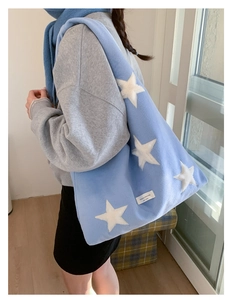 Detail shot of the blue plush star pattern tote bag with soft faux fur and brand label