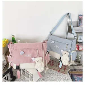 Detailed close-up of canvas messenger bag with cartoon badges and plush bear charms