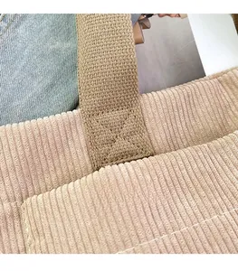 Close-up of precise stitching on khaki corduroy tote bag handle with striped texture