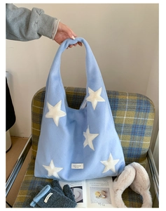 Detailed texture of light blue plush tote bag with white star patches and brand label