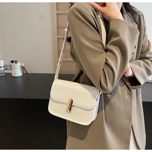 Detail of white square crossbody bag with metallic rotary lock and adjustable strap