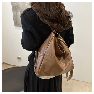 Brown leather tote bag shown on a model featuring spacious design and adjustable strap