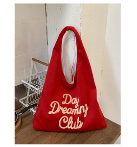 Detailed close-up of 3D towel embroidered Day Dreaming Club text on red tote bag