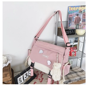 Detail of pink and white canvas messenger bag with astronaut badges and bear pendant