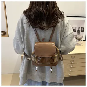 Close-up of vintage plaid bucket backpack showing brown leather and fashion print detail