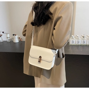 White minimalist square leather crossbody bag with a gold clasp on a fashion model