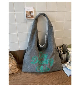Detail of grey felt tote bag featuring green Day Dreaming Club embroidery and soft texture