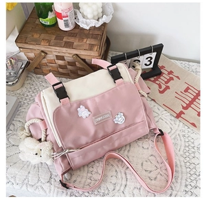 Detailed view of pink and white messenger bag with cute badges and a plush bear charm