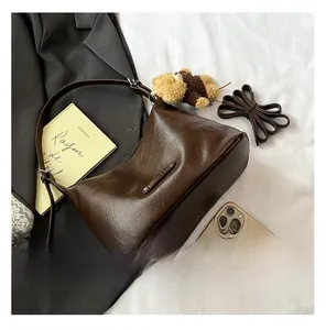 Detail der weichen dunkelbraunen Hobo-Tasche mit Bärenanhänger und Lederriemen