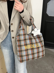 Detail of vintage plaid wool tote bag featuring yellow embroidery and a plush pendant