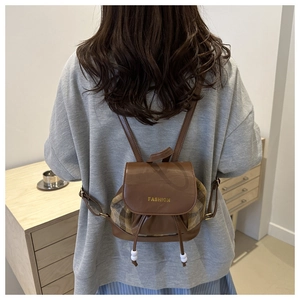 Detailed view of vintage plaid backpack with leather trim and gold fashion lettering