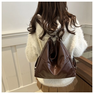 Rear view of a model wearing the dark brown vintage leather backpack with metal ring detail