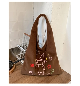 Detail of embroidered cartoon puppy and stars on brown plush tote bag for women
