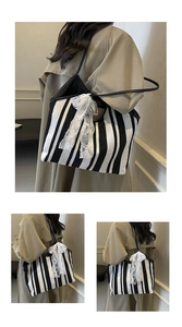 Detail of black and white striped tote bag with a white lace bow and leather strap