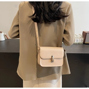 Detail view of cream square bag featuring a gold metal buckle on a khaki blazer