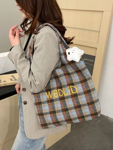 Close-up of retro plaid tote bag with yellow letter embroidery and a plush doll pendant