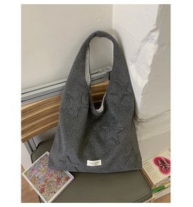 Detail of grey felt tote bag with star embroidery and brand tag on green chair