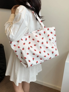 Lifestyle view of white nylon tote bag with strawberry print worn by a model