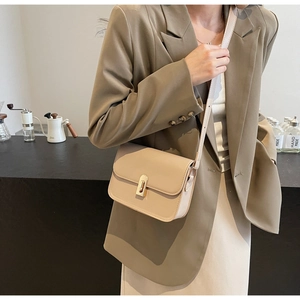 Detail of cream beige crossbody bag with golden metal buckle and fine stitching