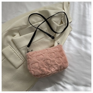 Détail du sac à main en peluche rose avec texture gaufrée cœur et bandoulière noire