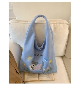 Detail of light blue plush tote bag featuring cute dog and floral star embroidery