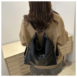 Detail of minimalist black PU leather convertible backpack showing silver metal buckle straps