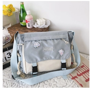 Detail of blue and white canvas messenger bag featuring astronaut cat badges and wide strap