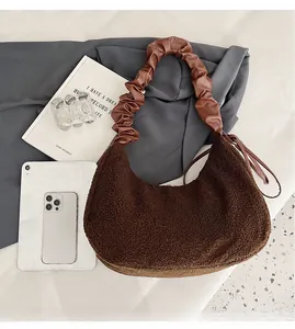 Brown faux fur half-moon bag featuring a pleated leather shoulder strap in a winter style