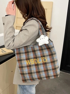 Close-up of vintage plaid tote bag featuring yellow embroidery and a star plush charm