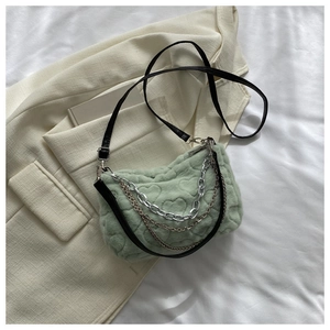 Détail du sac en peluche vert clair avec motifs de cœurs et chaînes métalliques décoratives
