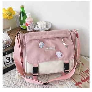 Detailed view of pink and white canvas messenger bag with cute badges and buckle straps