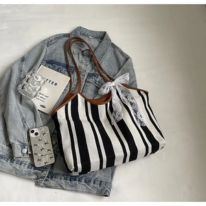 Detail of canvas tote bag with black and white stripes and brown leather trim accents