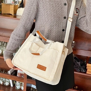 Large beige corduroy tote bag with brown leather accents and adjustable wide shoulder strap