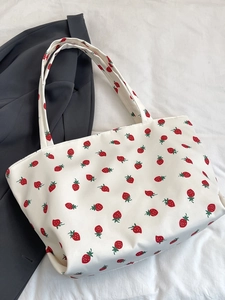 Detailed close-up of nylon tote bag with red strawberry print on white canvas surface