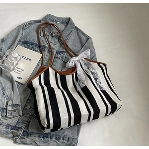Close-up of black and white striped canvas tote with brown leather handles and lace bow