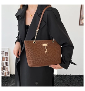 Detail showing the brown leopard print tote bag texture with a gold deer pendant