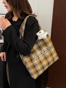 Detail of vintage plaid tote bag with letter embroidery and star plush pendant