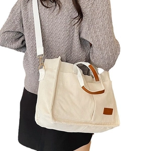 Large beige corduroy tote bag with brown leather handles and wide white shoulder strap